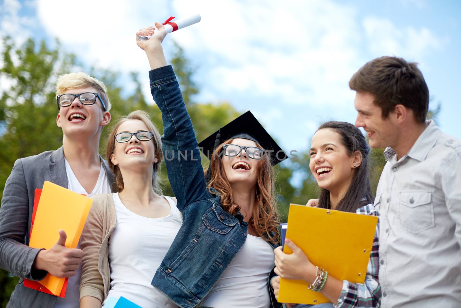 education, graduation and people concept - group of smiling students in mortarboard with diploma and school folders