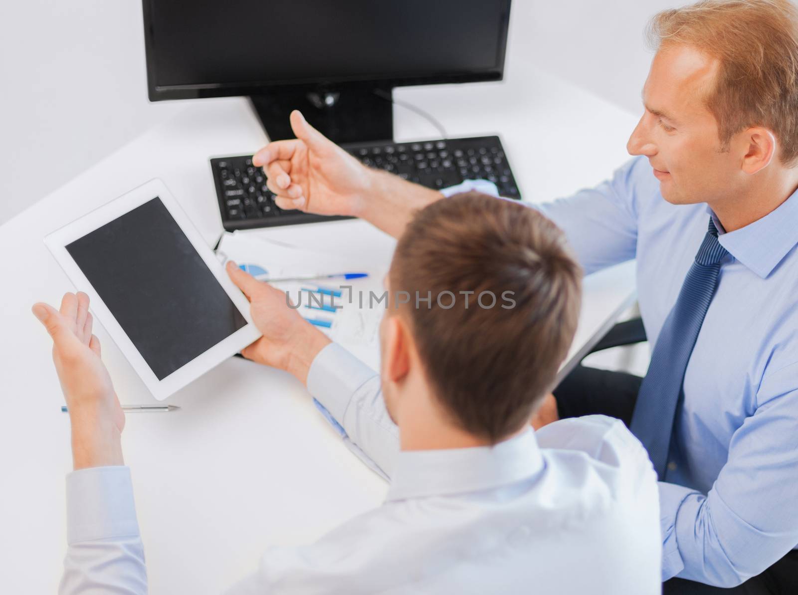 businesss and office concept - businessmen with notebook and tablet pc discussing graphs on meeting