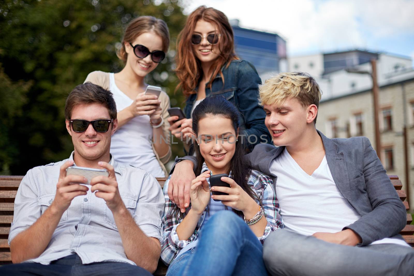 summer, technology, education and teenage concept - group of happy students or teenagers with smarphones taking selfie and texting messages at campus