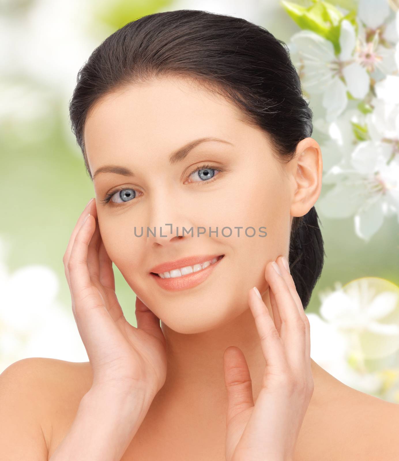 beauty, people and health concept - beautiful young woman touching her face over green blooming garden background
