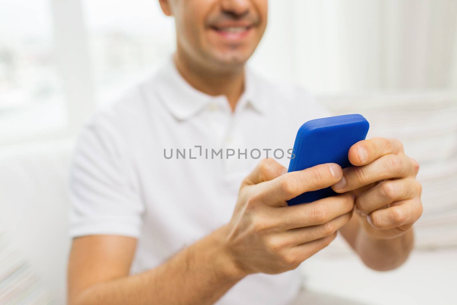 close up of happy man with smartphone at home by dolgachov