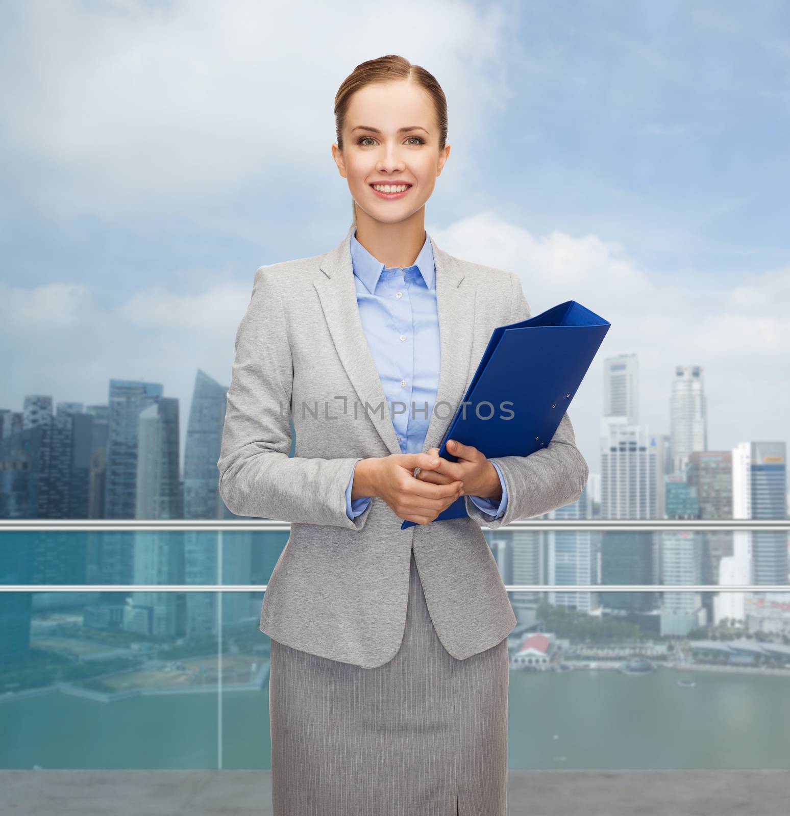business, people and real estate concept - smiling young businesswoman holding folder over city background