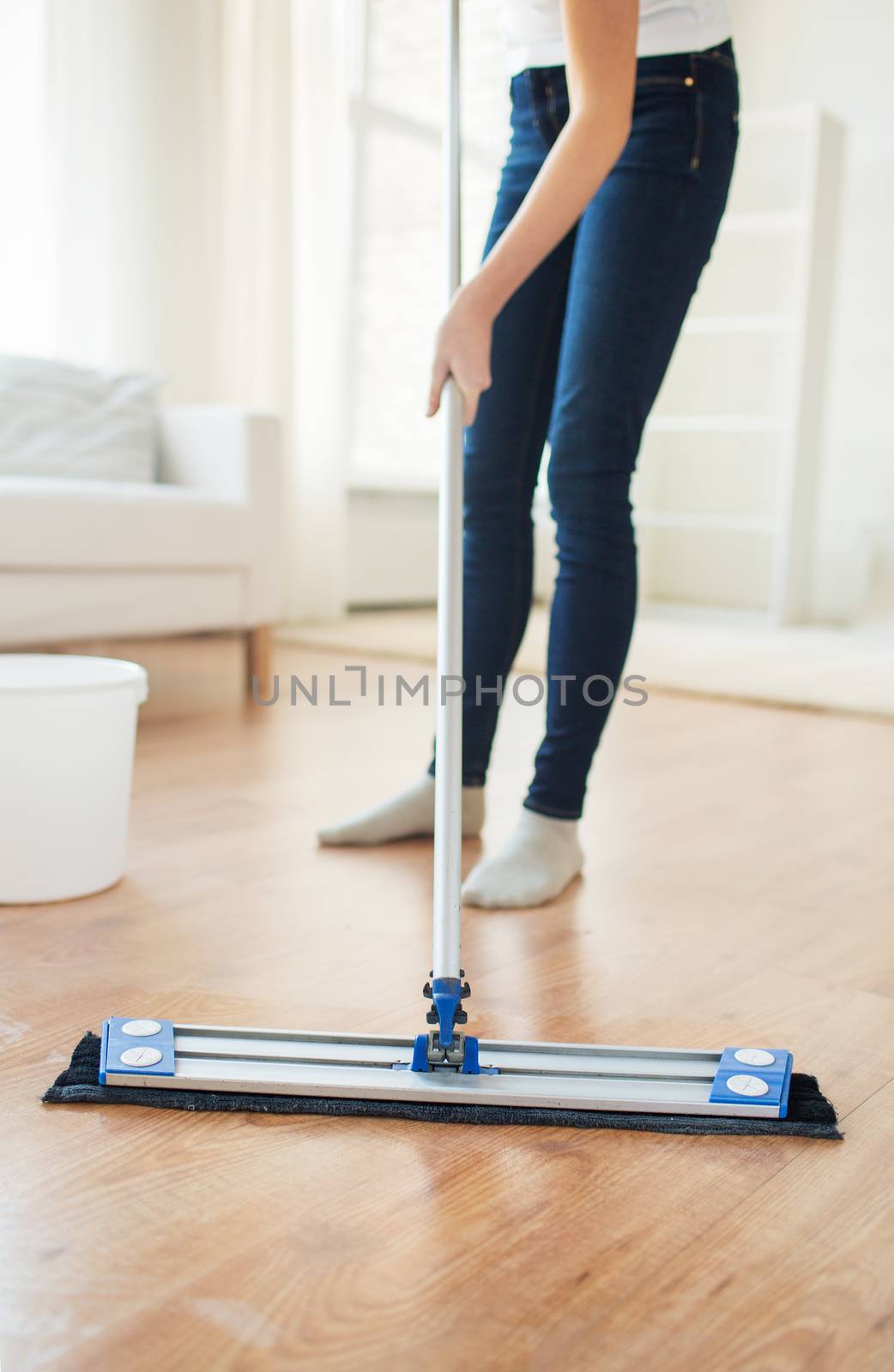 people, housework and housekeeping concept - close up of woman legs with mop cleaning floor at home