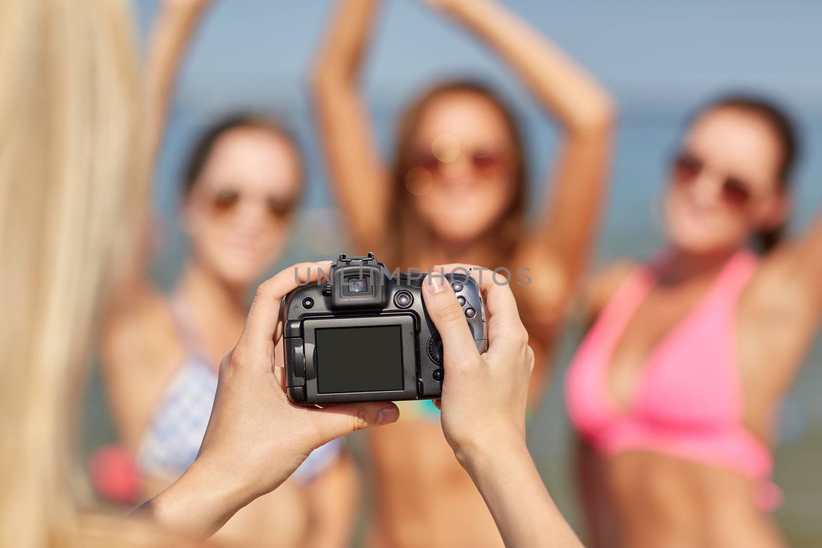 close up of smiling women photographing on beach by dolgachov