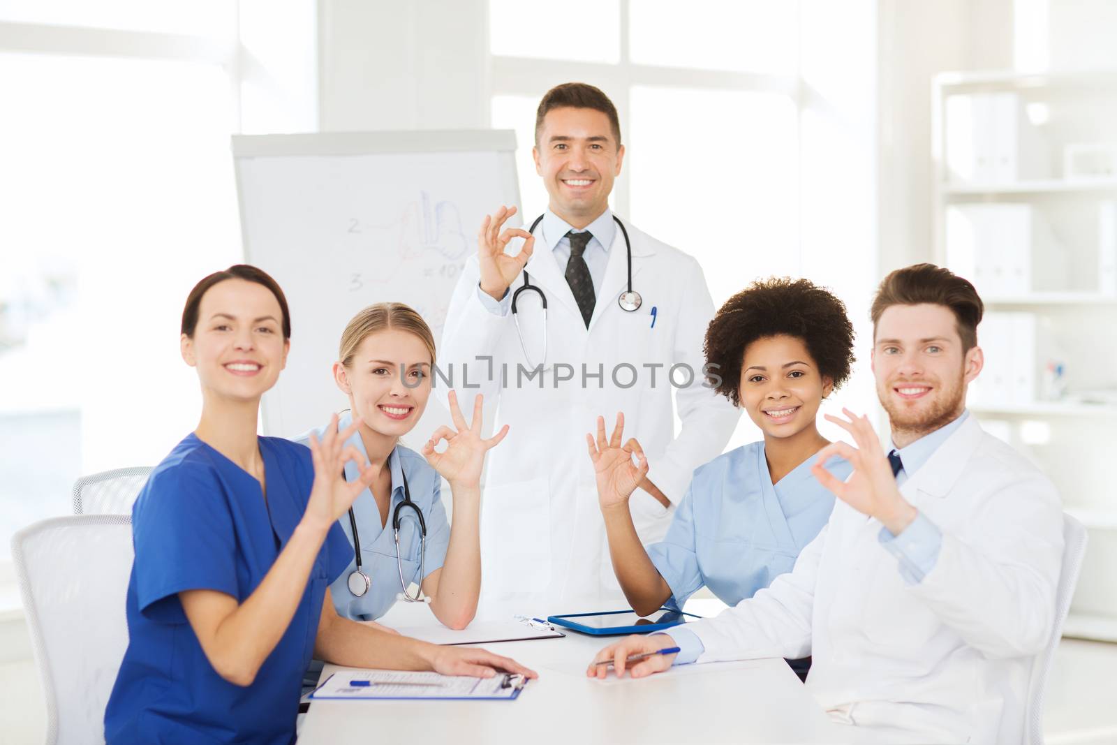 hospital, profession, medical education, people and medicine concept - group of happy doctors meeting on presentation or conference at hospital and showing ok hand sign