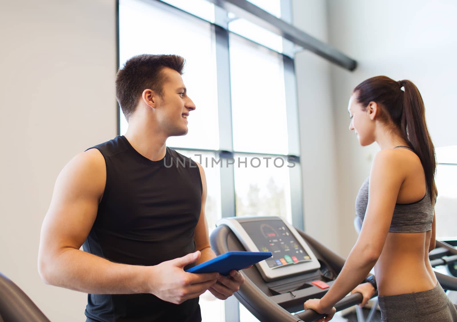 happy woman with trainer on treadmill in gym by dolgachov