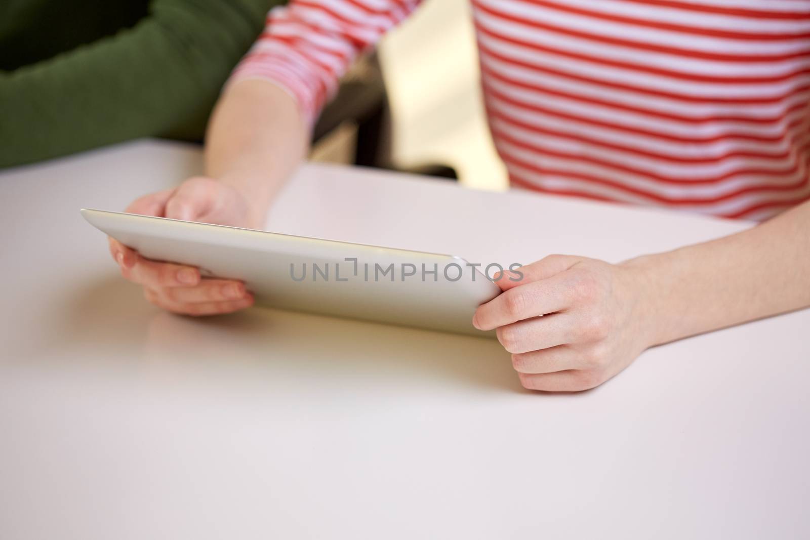 close up of female hands with tablet pc at table by dolgachov