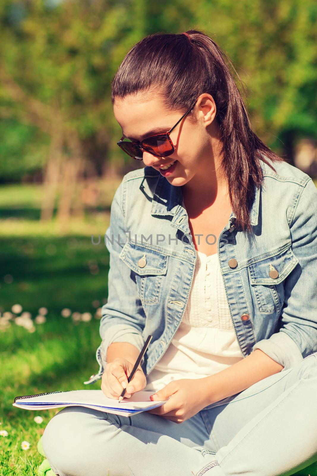 smiling young girl with notebook writing in park by dolgachov