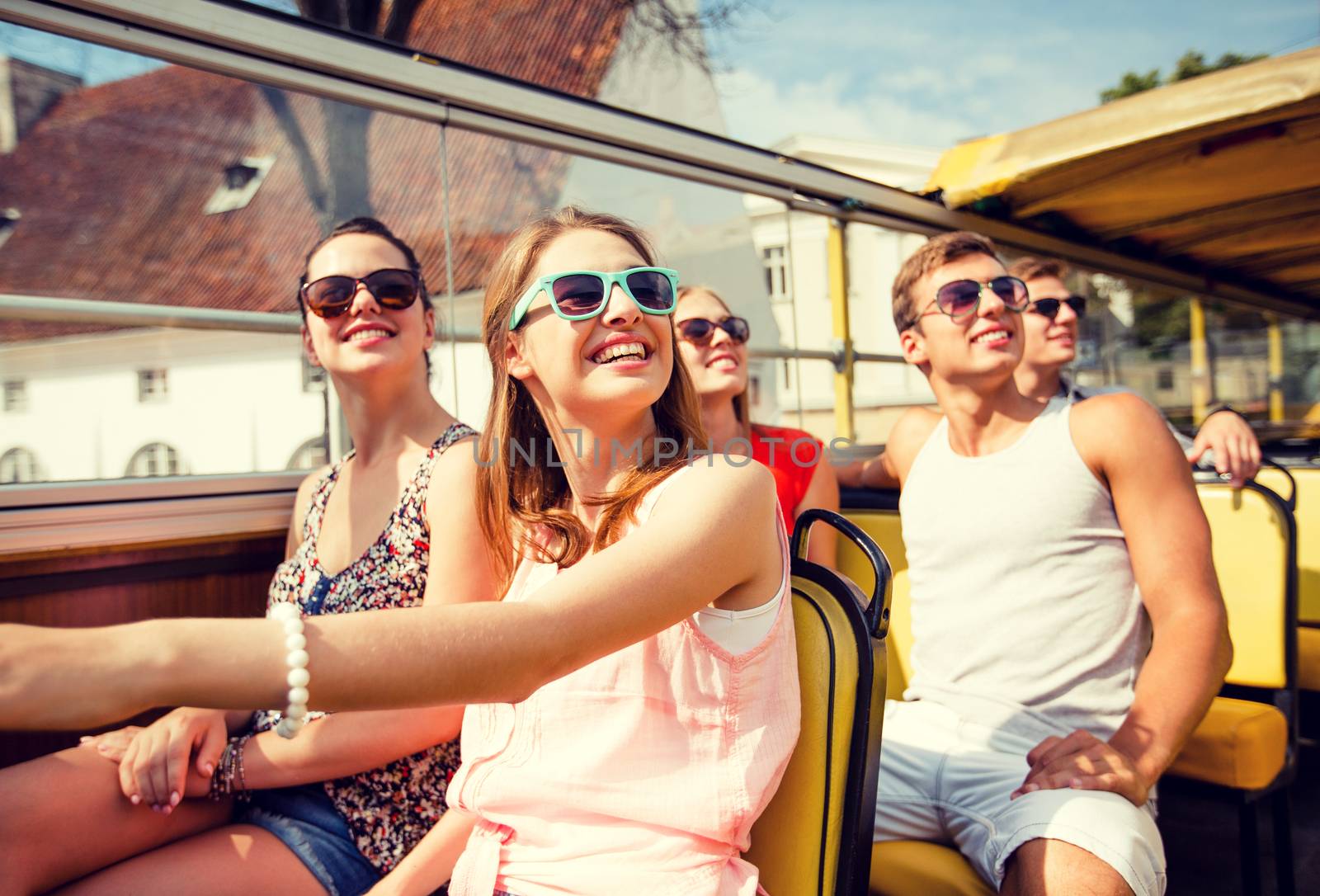 friendship, travel, vacation, summer and people concept - group of smiling friends traveling by tour bus