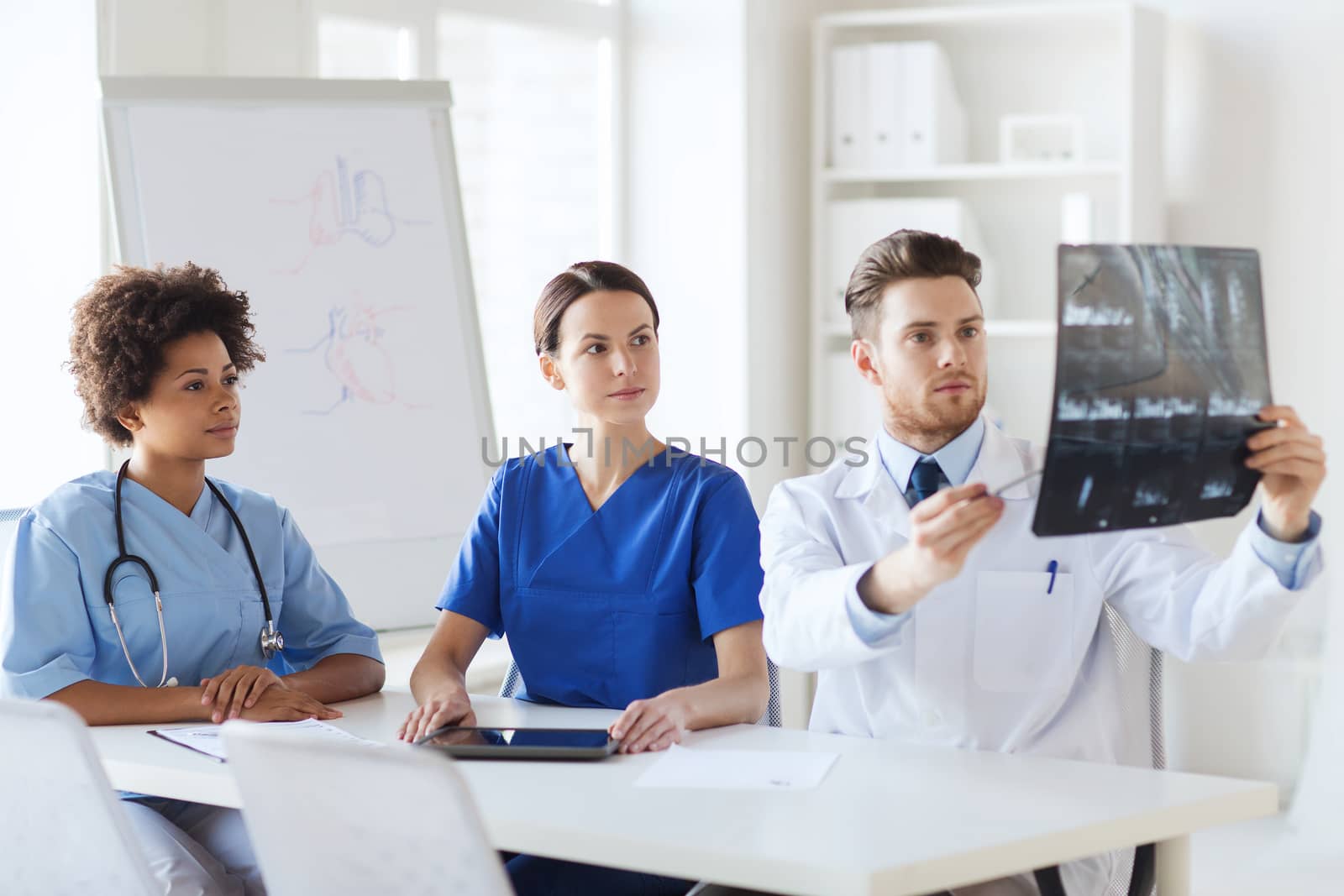 radiology, people and medicine concept - group of doctors looking to and discussing x-ray image at hospital