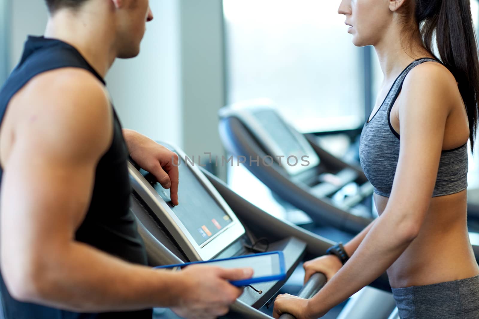 close up of woman with trainer on treadmill in gym by dolgachov