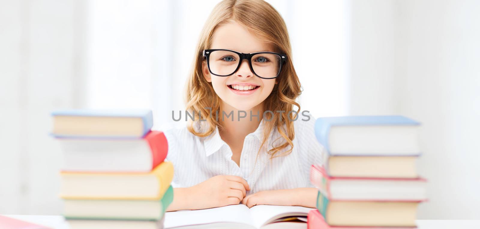 education and school concept - little student girl studying and reading books at school