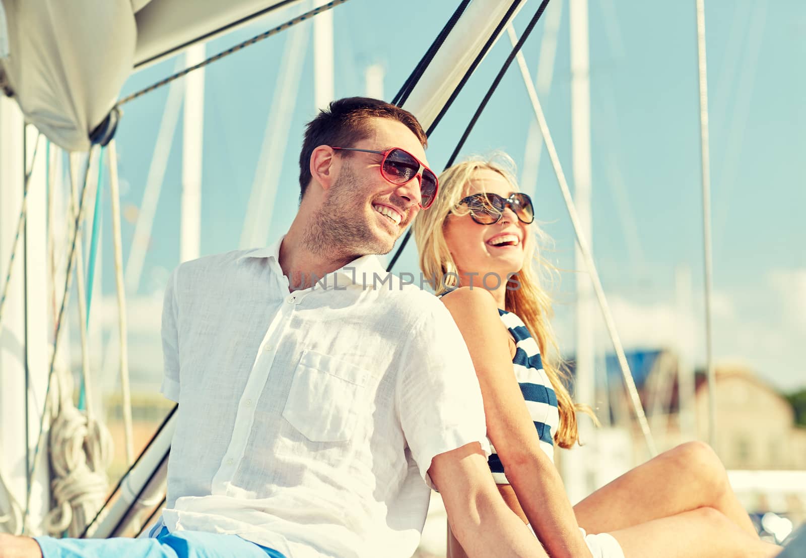 vacation, travel, sea, friendship and people concept - smiling couple sitting and talking on yacht deck