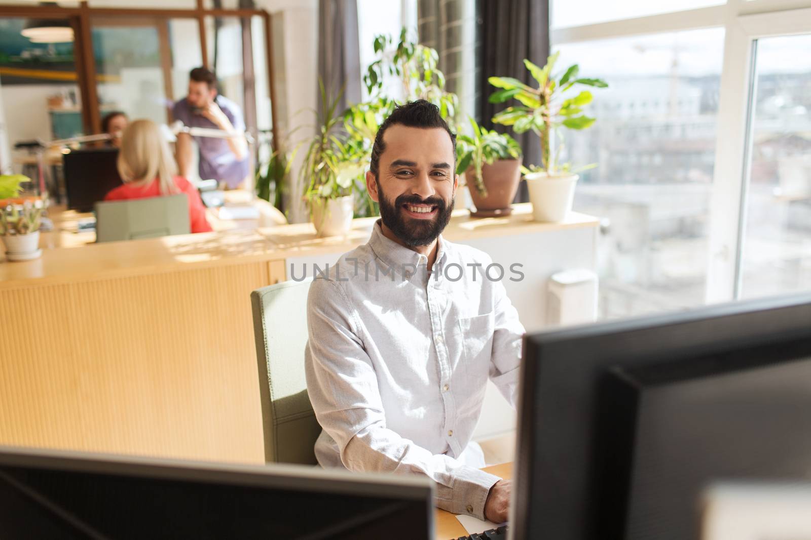 happy creative male office worker with computer by dolgachov