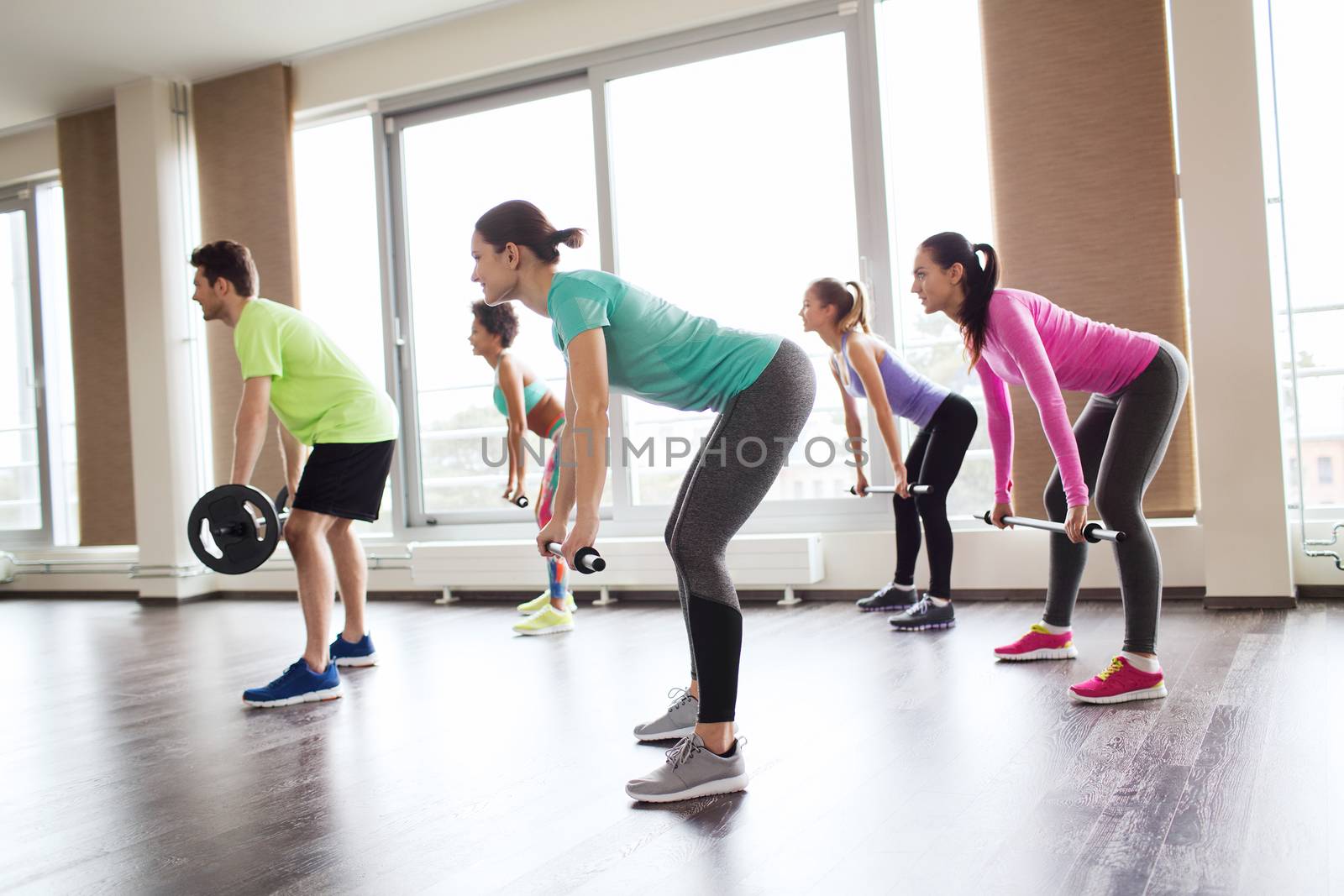 fitness, sport, training, gym and lifestyle concept - group of people exercising with barbell and bars in gym