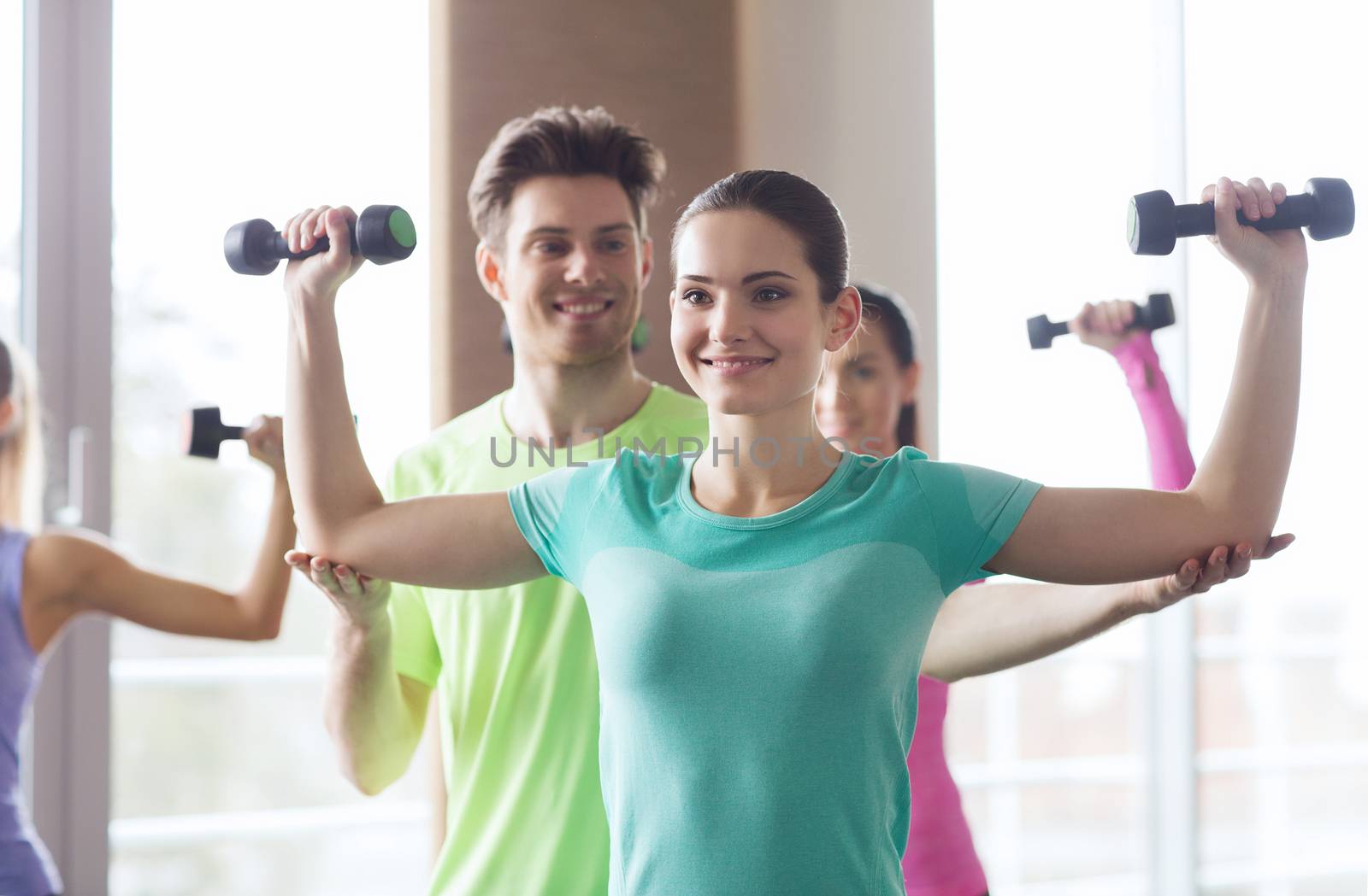 happy women and trainer with dumbbells in gym by dolgachov