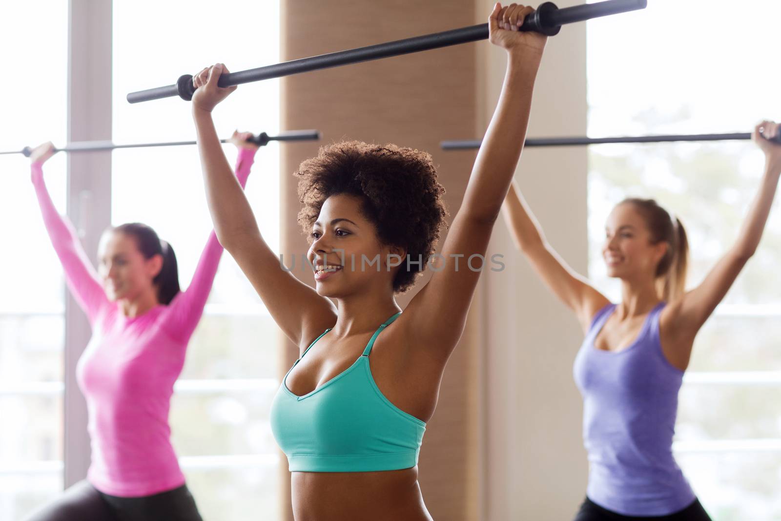 group of people exercising with bars in gym by dolgachov
