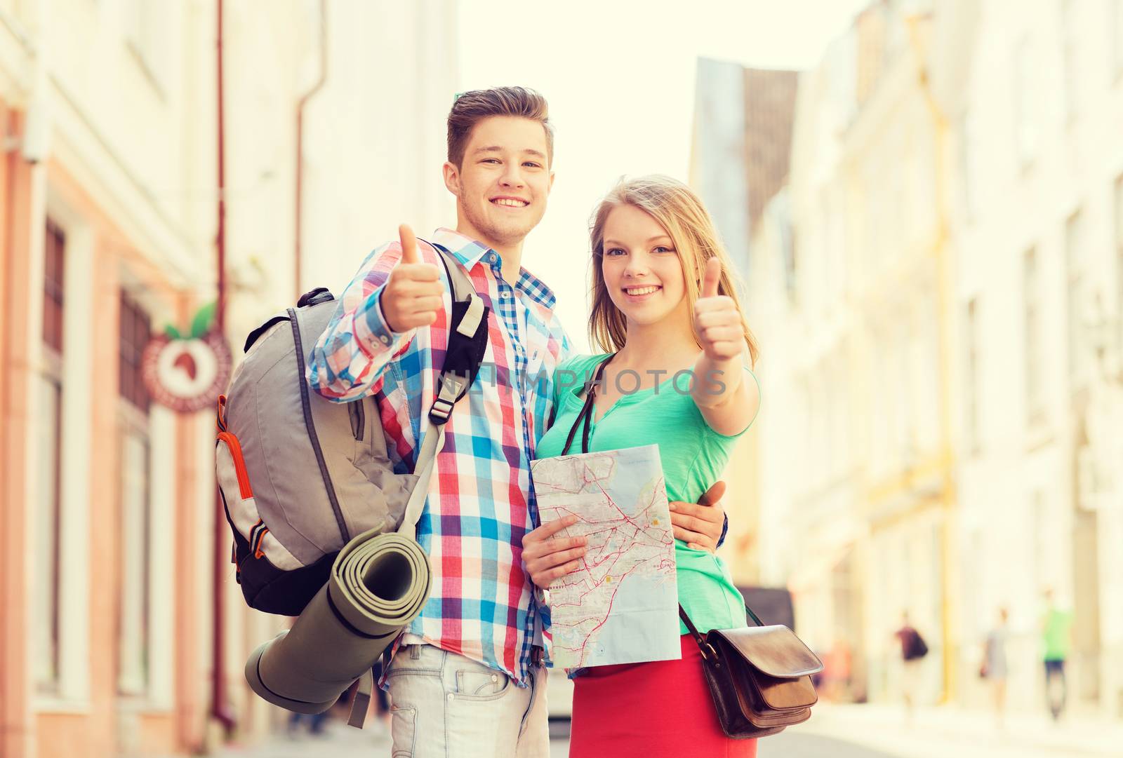 travel, vacation, gesture and friendship concept - smiling couple with map and backpack showing thumbs up in city