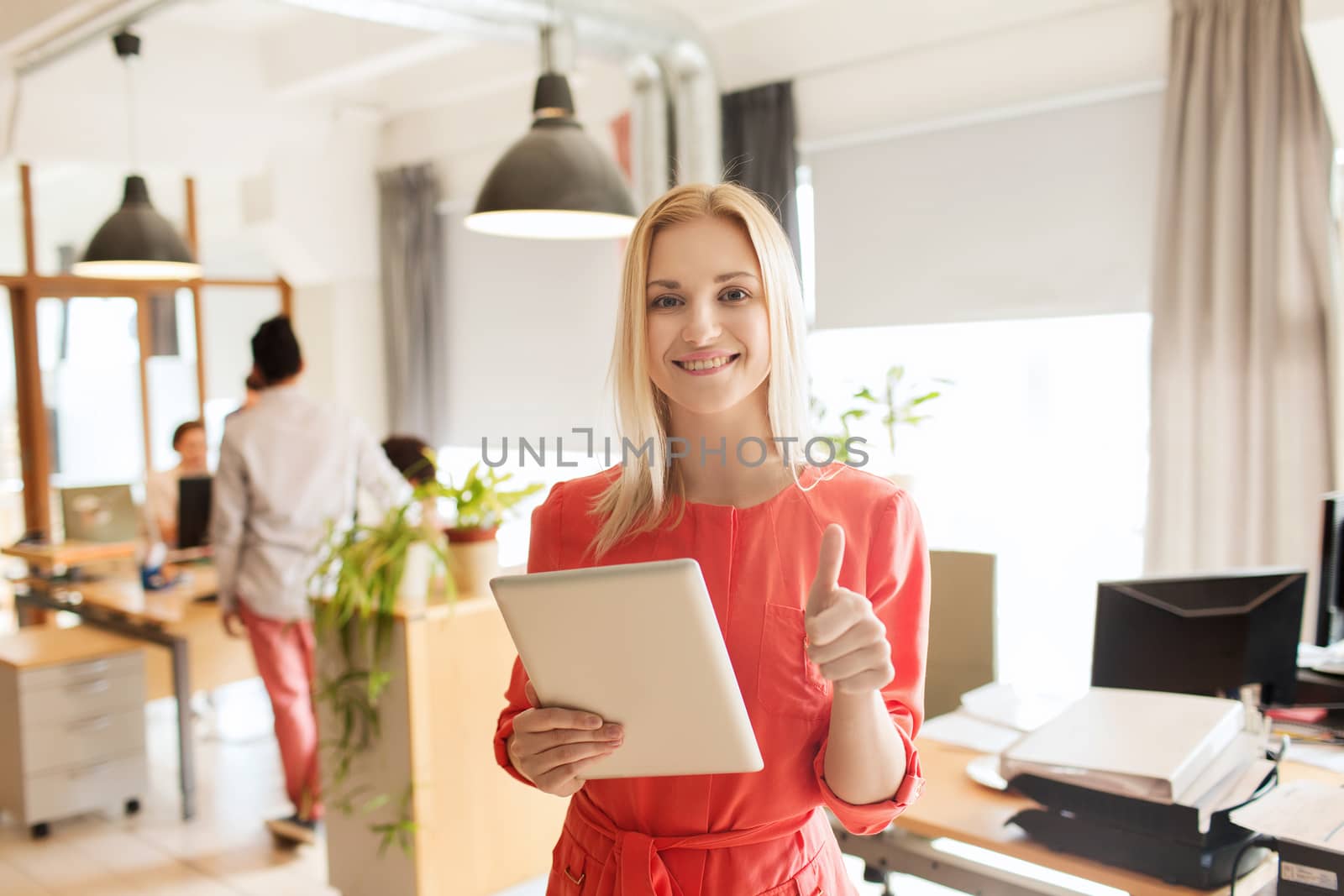 woman with tablet pc showing thumbs up at office by dolgachov