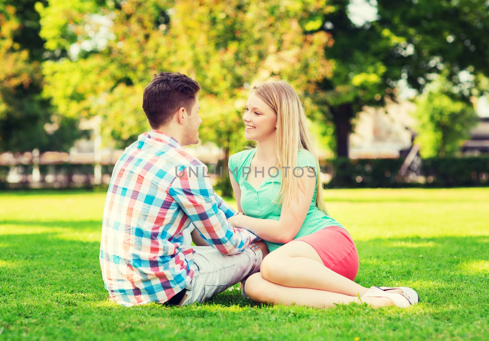 smiling couple sitting on grass in park by dolgachov