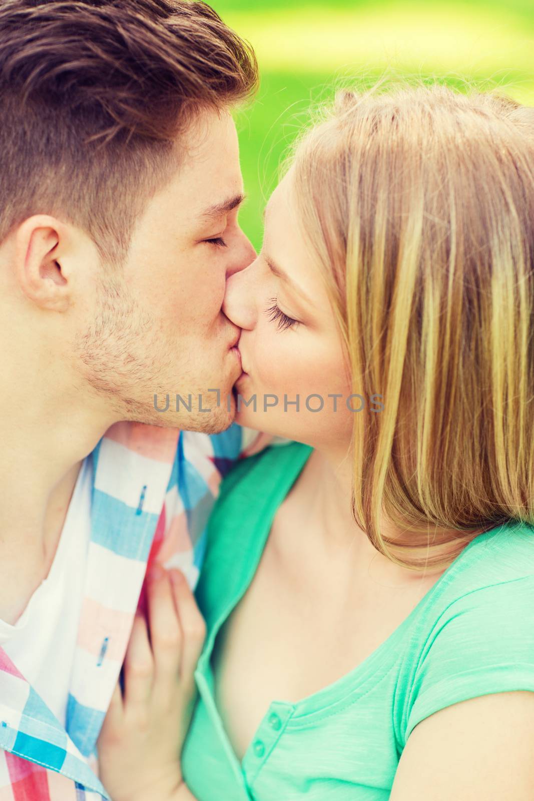 holidays, vacation, love and friendship concept - smiling couple kissing and hugging in park