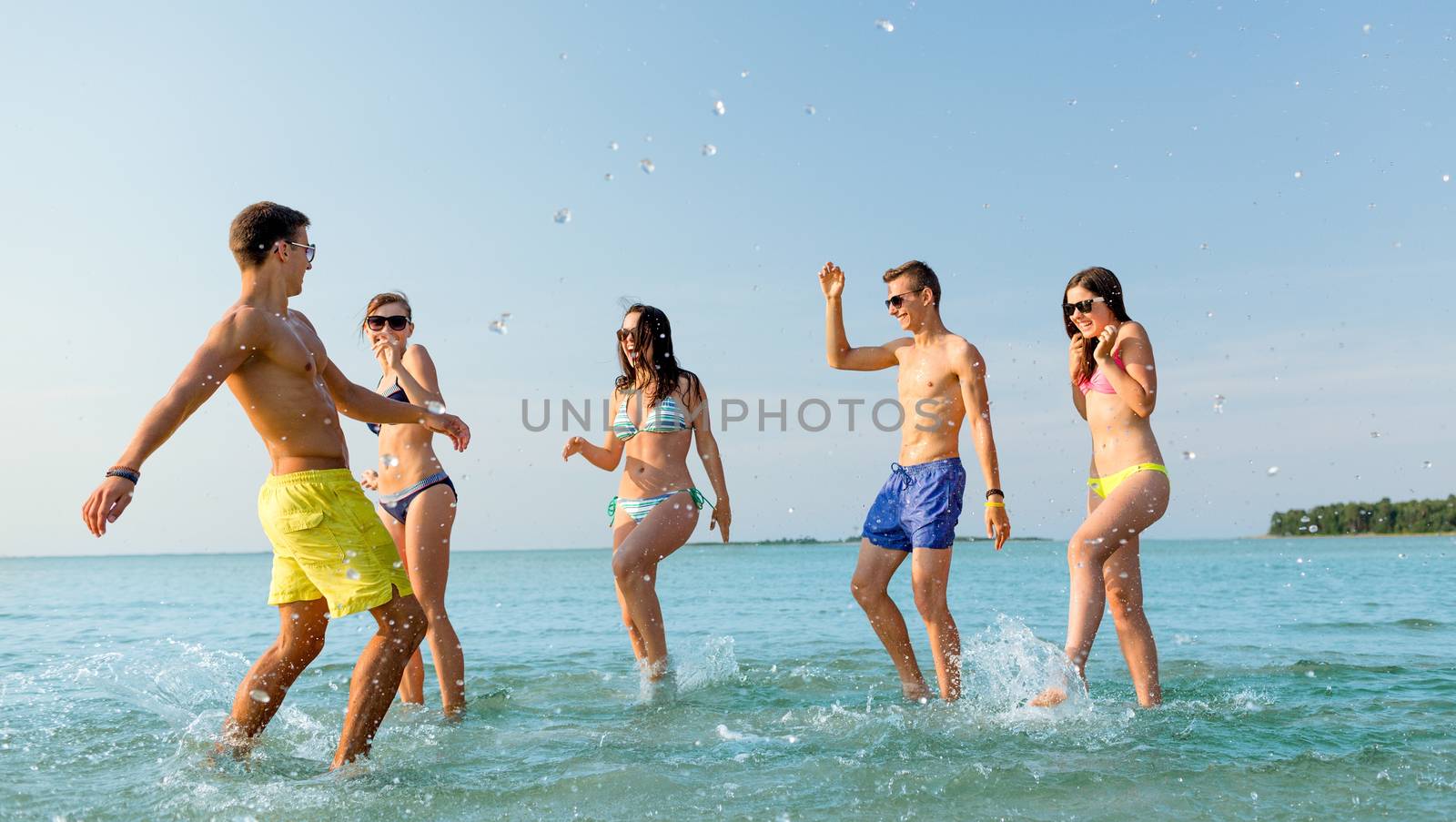 friendship, sea, summer vacation, holidays and people concept - group of happy friends having fun on beach