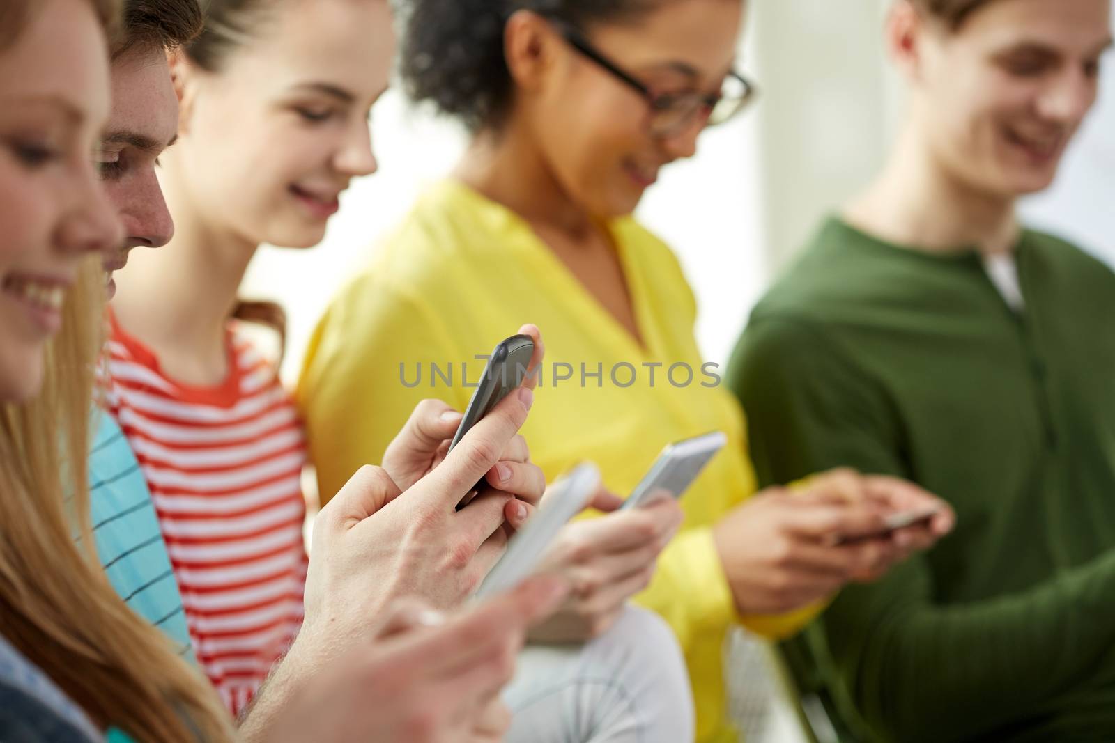 education, people and technology concept - close up of smiling students with smartphones at school