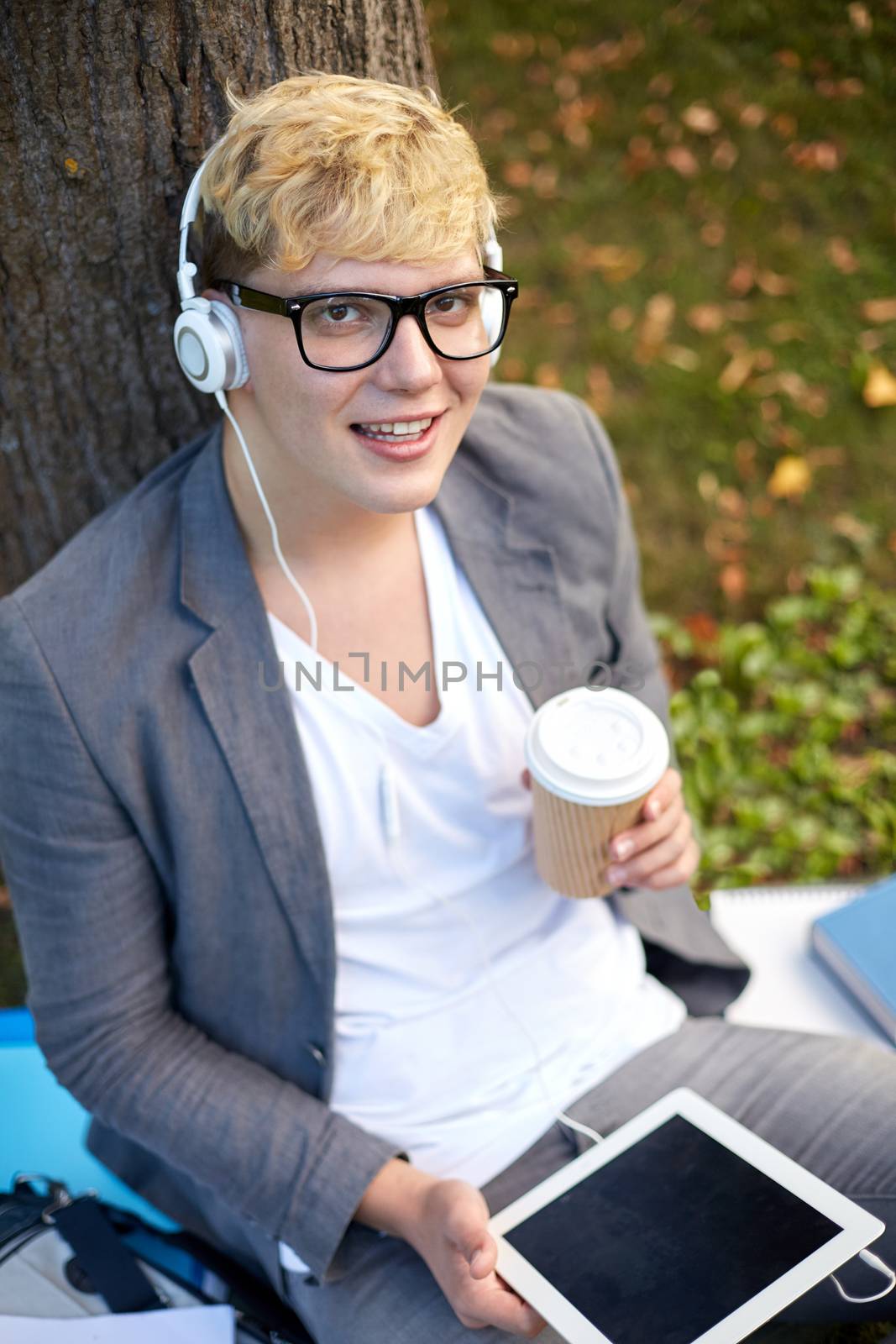 happy teenage boy in headphones with tablet pc by dolgachov