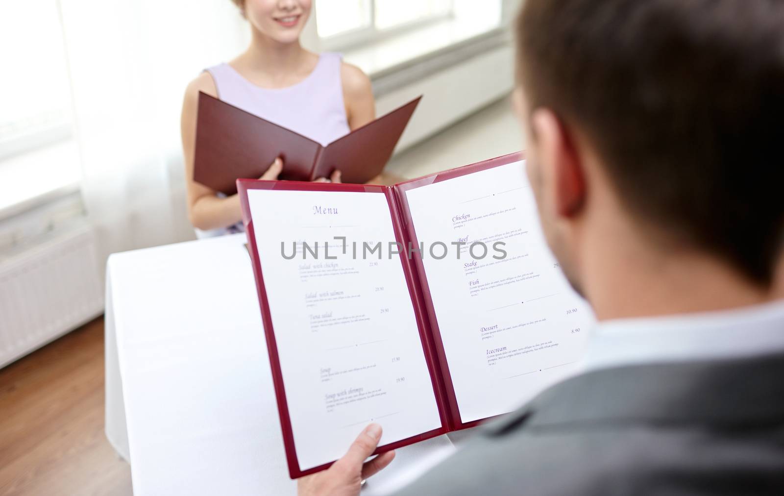 restaurant, food, eating and holiday concept - close up of couple with menu choosing dishes at restaurant