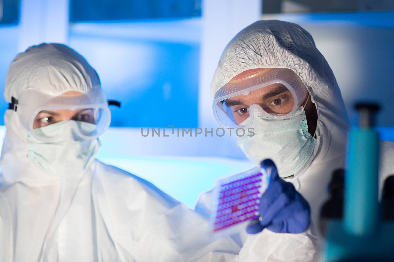 science, chemistry, medicine, research and people concept - close up of scientists looking at test sample plate in chemical laboratory