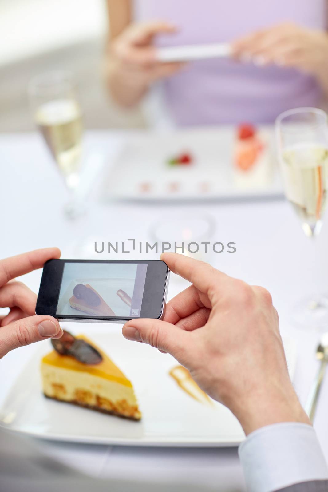 people, leisure, eating and technology concept - close up of couple with smartphones taking picture of food at restaurant