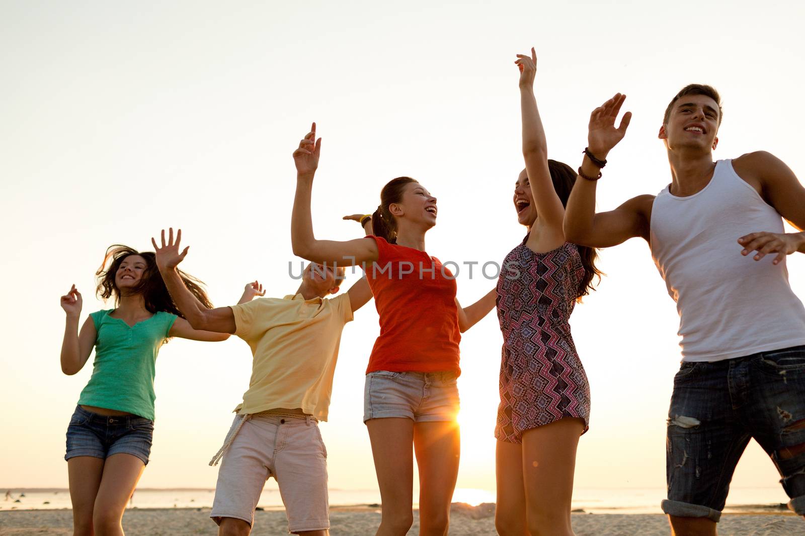 friendship, summer vacation, holidays, party and people concept - group of smiling friends dancing on beach