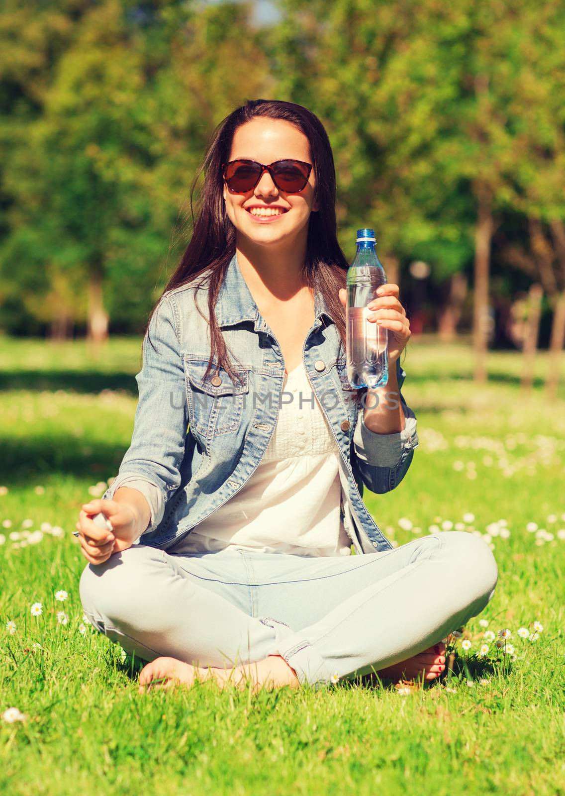 smiling young girl with bottle of water in park by dolgachov