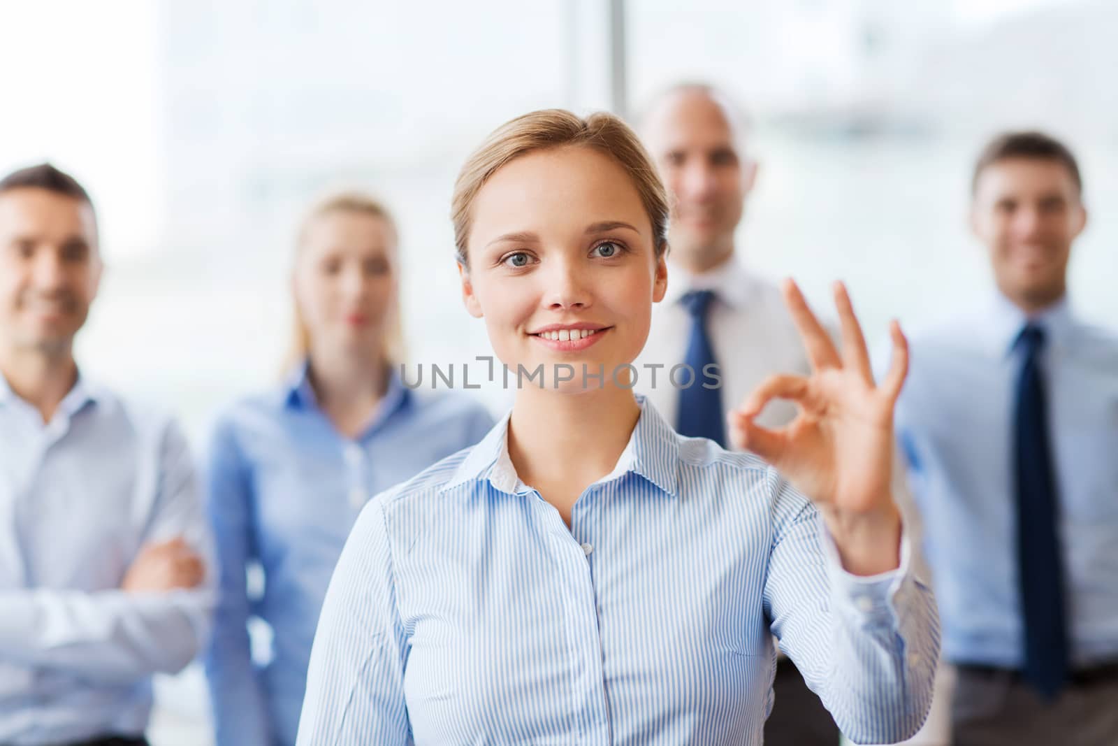 smiling businesswoman showing ok sign in office by dolgachov