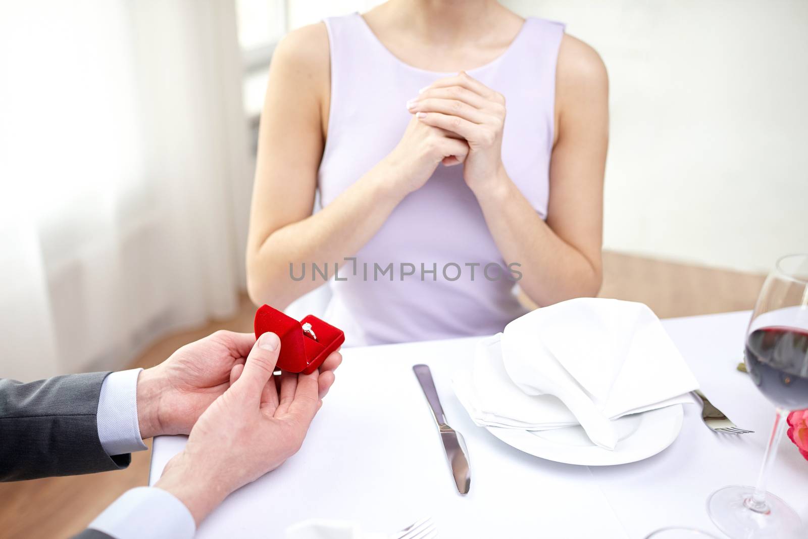 couple, love, engagement and holiday concept - close up of excited young woman and boyfriend giving her ring at restaurant
