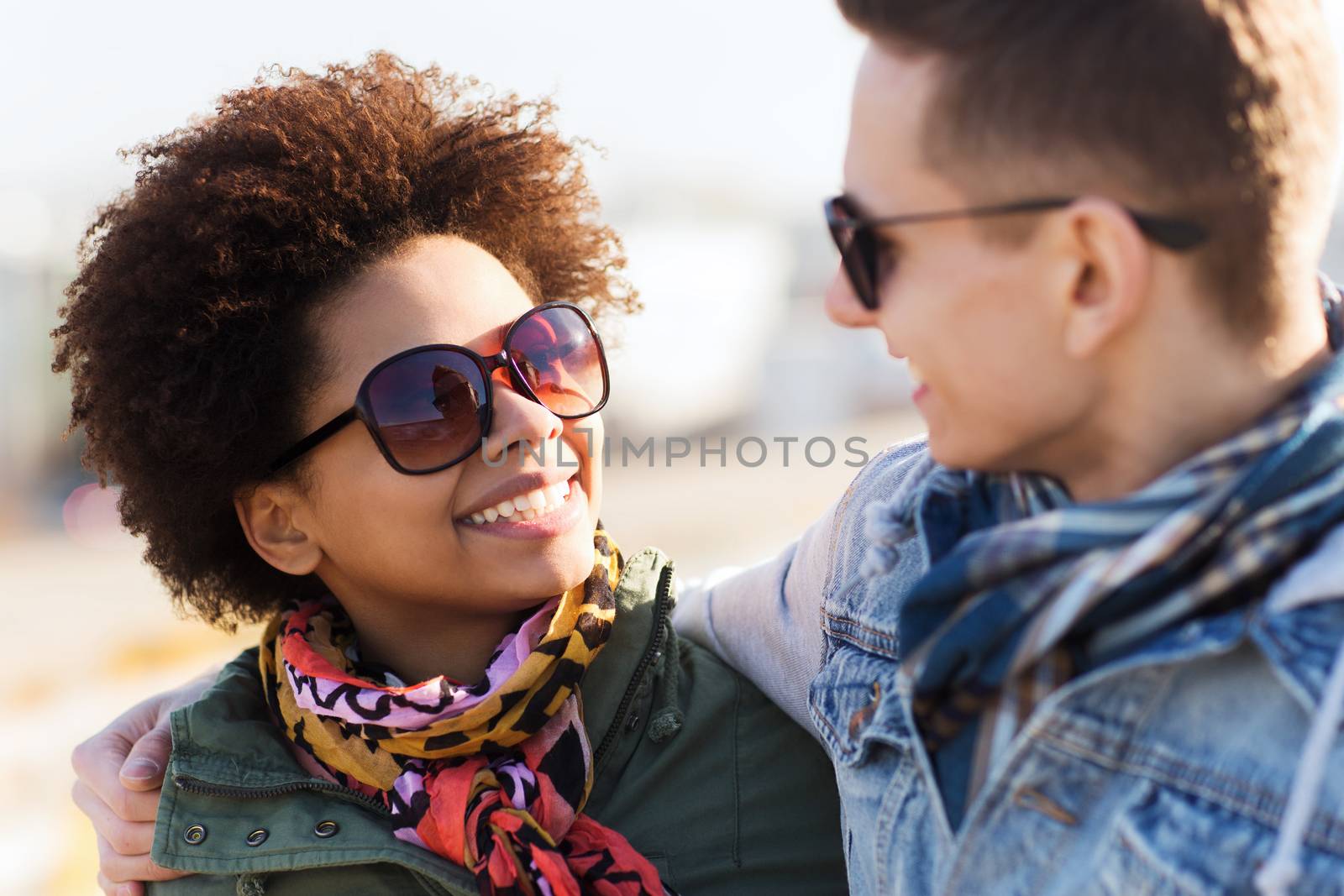 happy teenage friends in shades talking outdoors by dolgachov