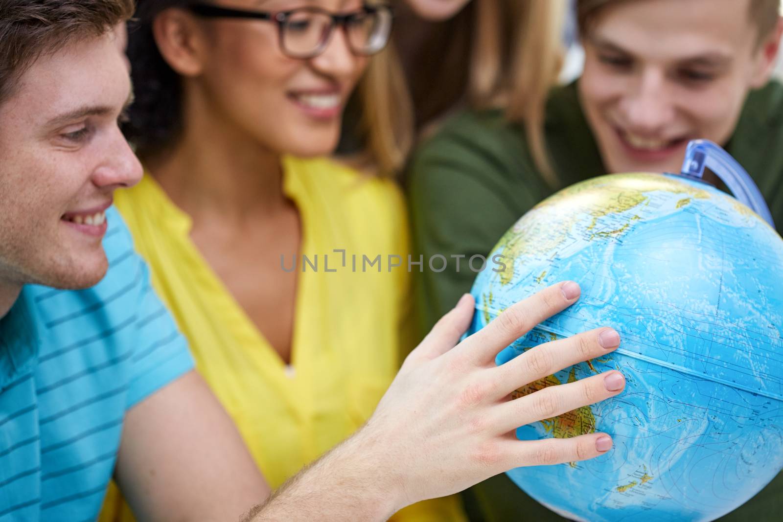 education, geography subject, high school, teamwork and people concept - group of smiling students looking at globe