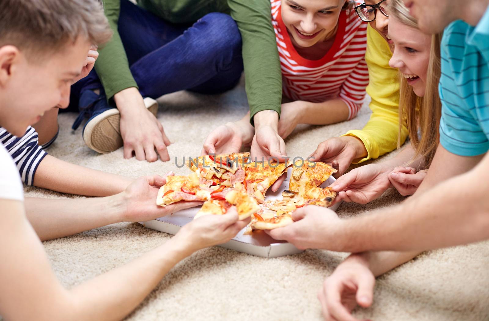 food, leisure and friendship concept - close up of happy teenage friends eating pizza at home