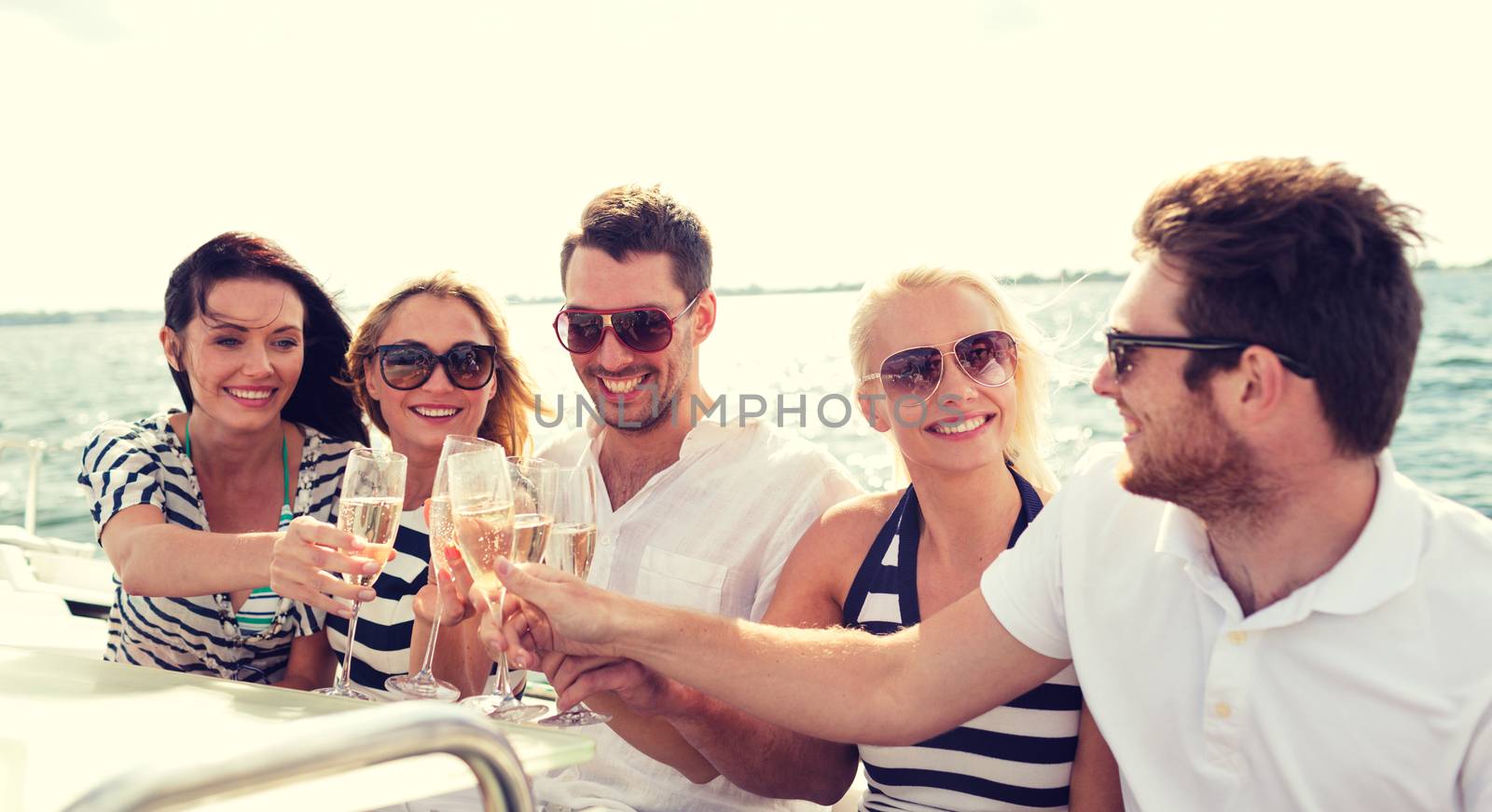 smiling friends with glasses of champagne on yacht by dolgachov