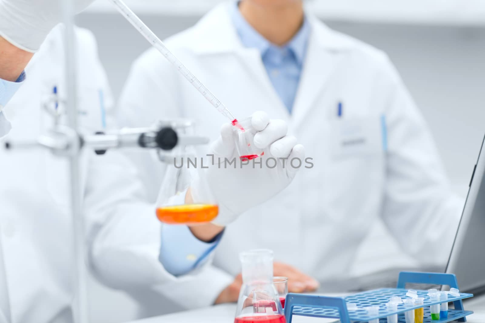 close up of scientists filling test tube in lab by dolgachov