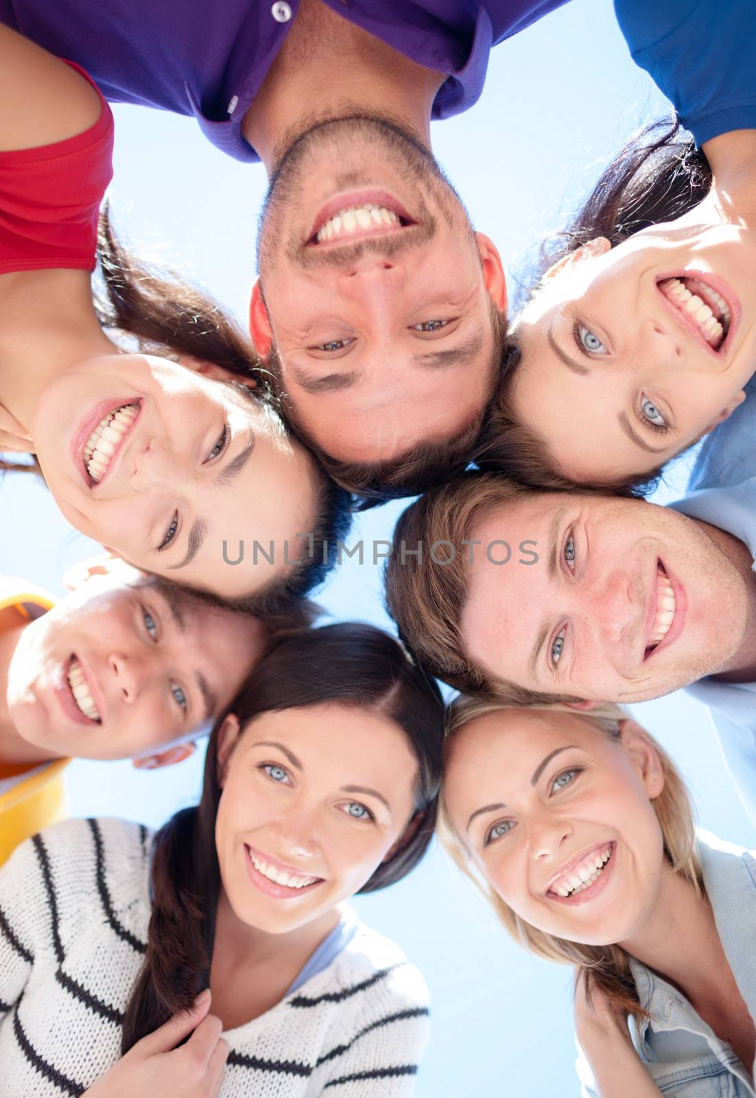 friendship, summer vacation, holidays and people concept - group of smiling friends standing in circle over blue sky