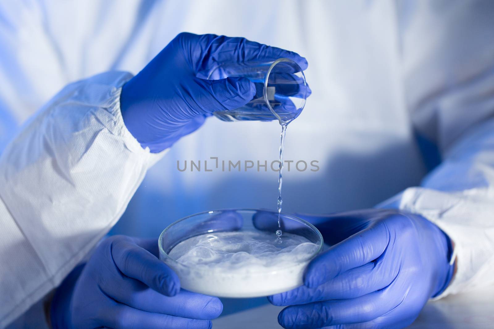 close up of scientists hands with chemicals in lab by dolgachov