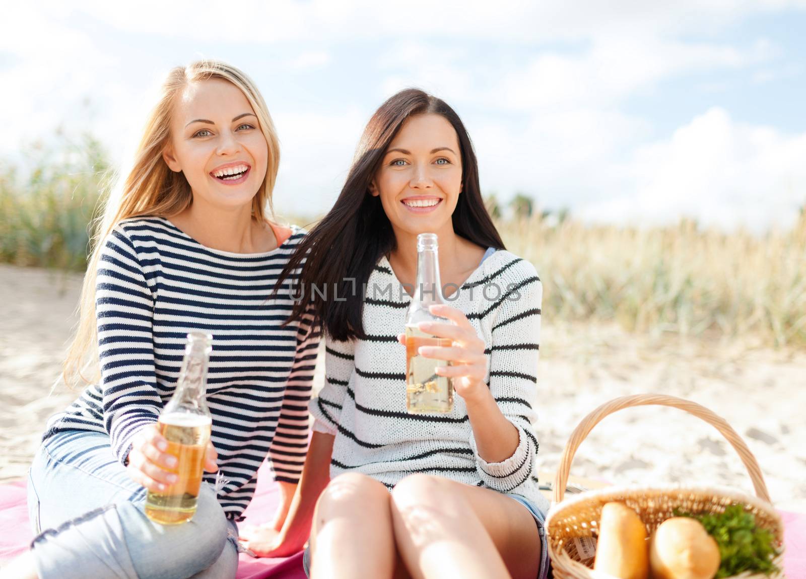 happy young women drinking beer on beach by dolgachov