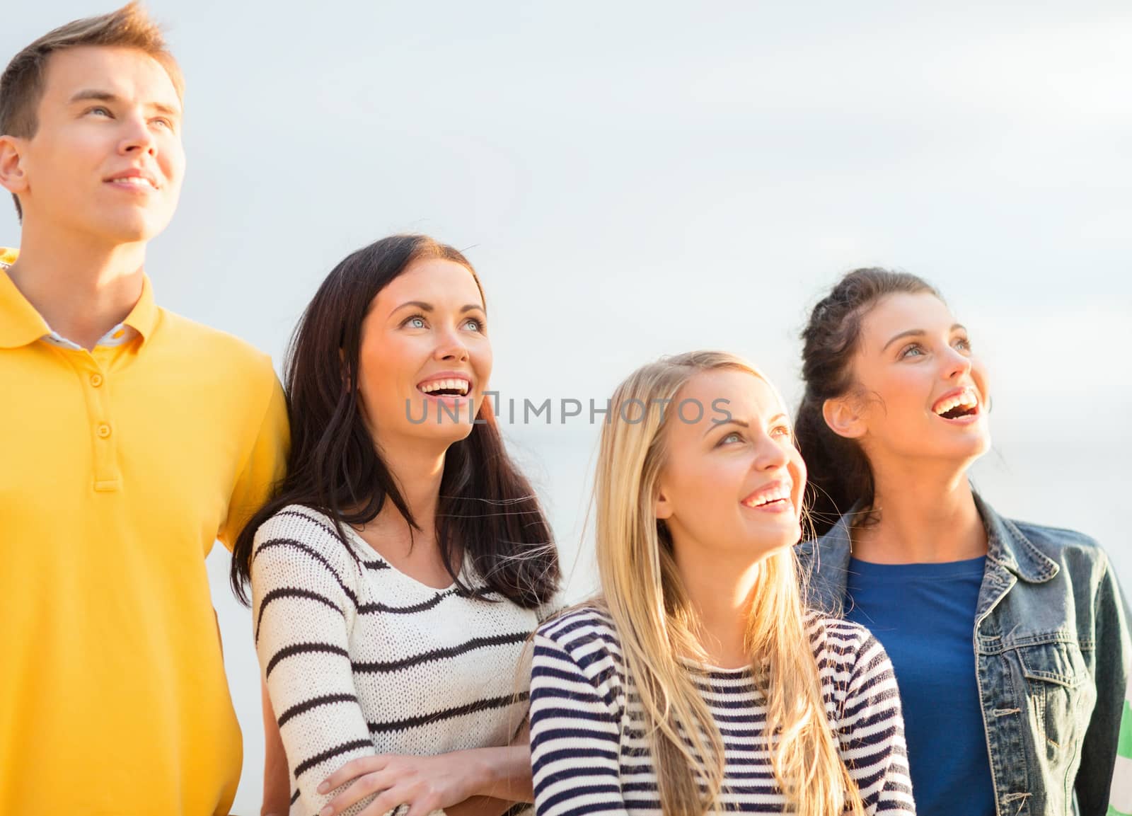group of happy friends looking up on beach by dolgachov