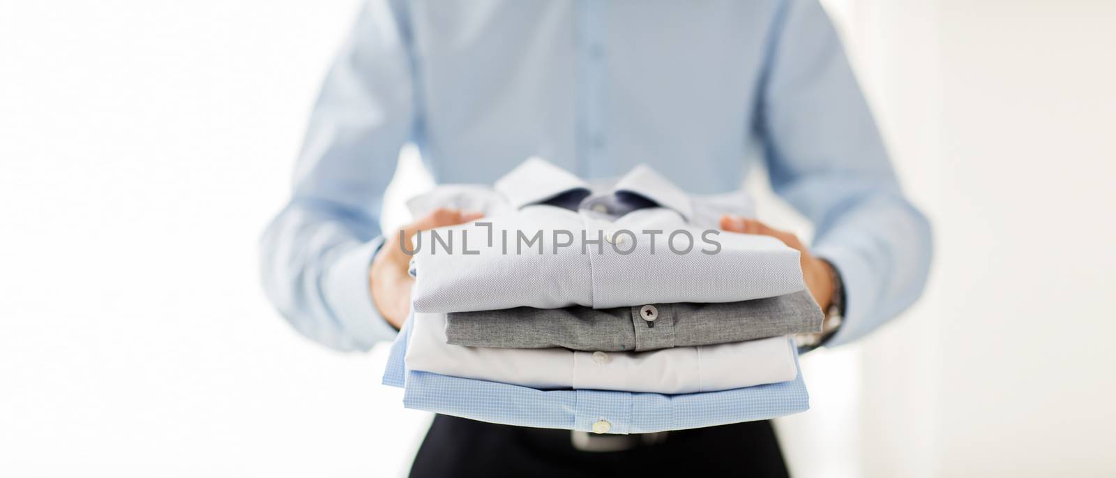 close up of businessman holding folded shirts by dolgachov