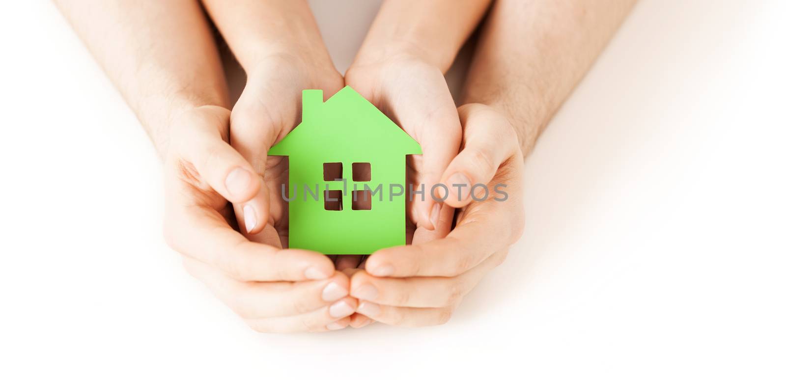 real estate and family home concept - closeup picture of male and female hands holding green blank paper house