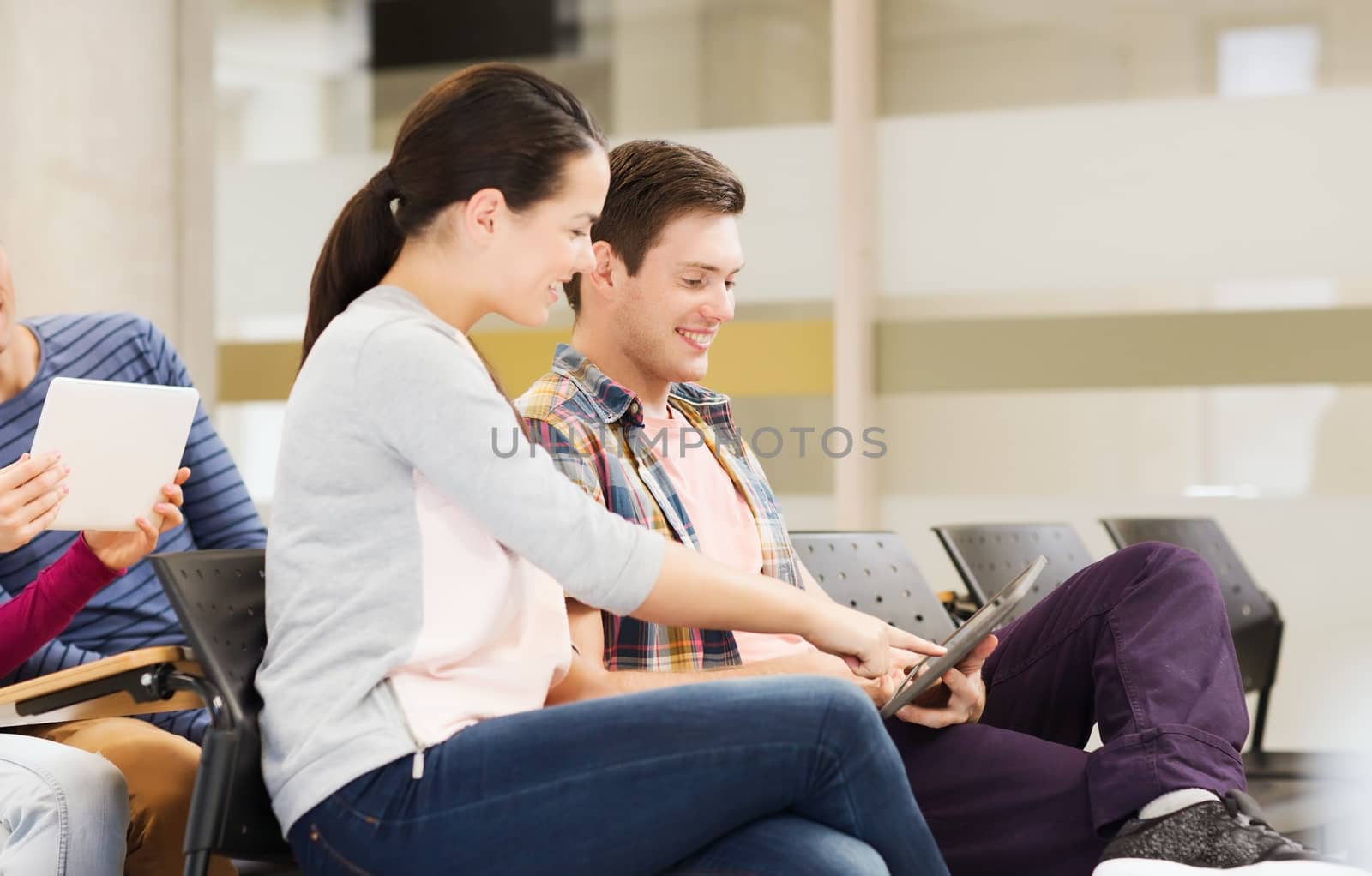 education, high school, teamwork and people concept - group of smiling students with tablet pc computers sitting in lecture hall