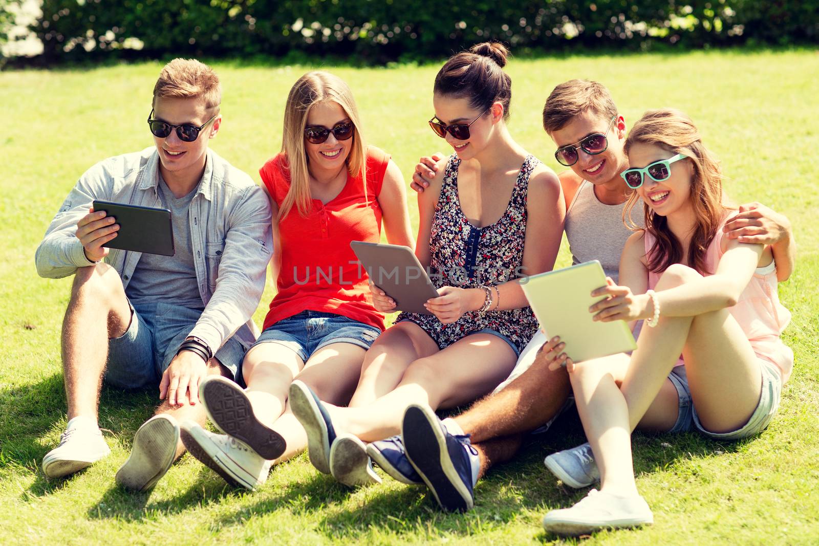smiling friends with tablet pc computers in park by dolgachov