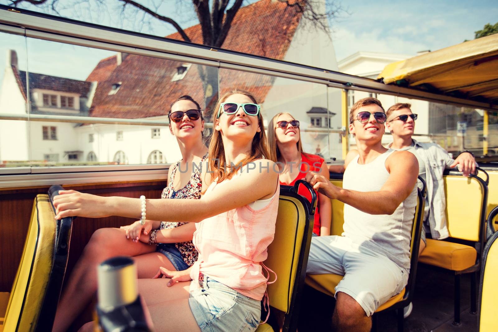 friendship, travel, vacation, summer and people concept - group of smiling friends traveling by tour bus