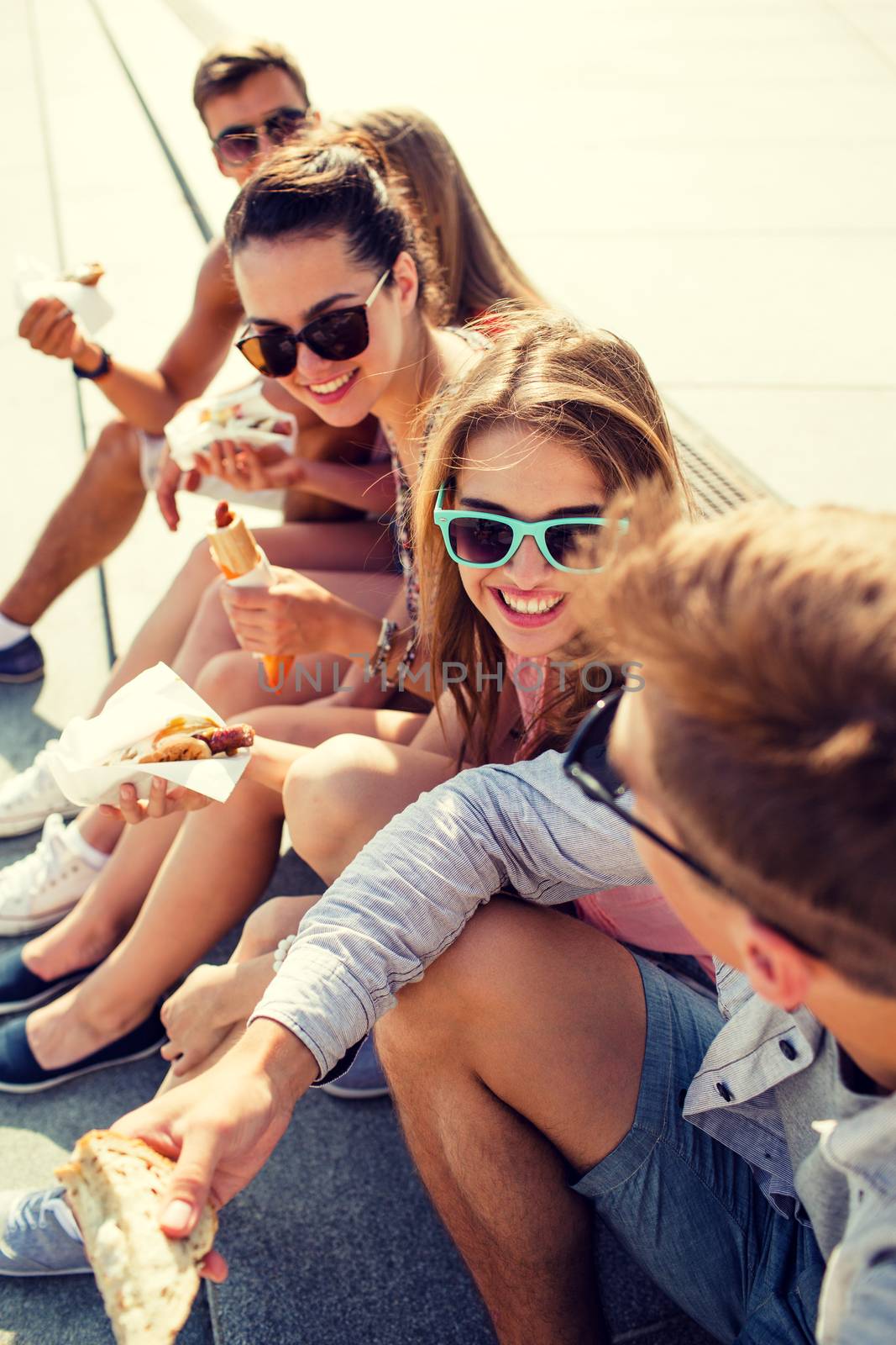 friendship, leisure, summer and people concept - group of smiling friends in sunglasses sitting with food on city square